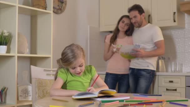 Glückliche Eltern, die stolz ihrer klugen Tochter bei den Hausaufgaben zusehen, Familie — Stockvideo