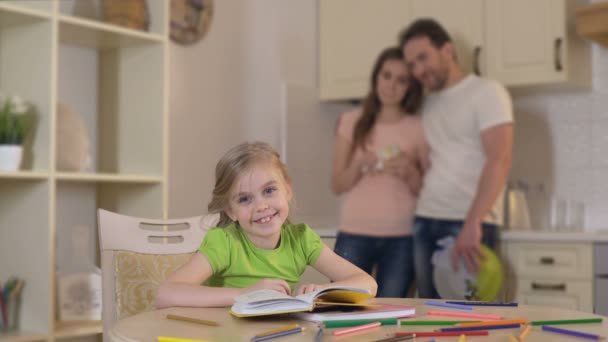 Chica feliz sonriendo para la cámara, padres cariñosos abrazando y mirando a la hija — Vídeos de Stock