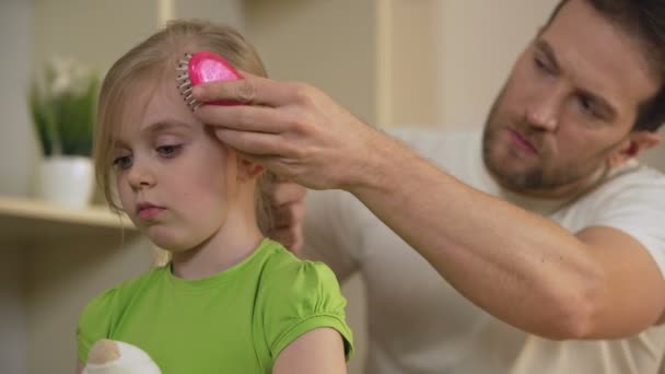 Strenger Vater kämmt traurige kleine Tochter mit ernstem Gesicht, Haustyrann — Stockvideo