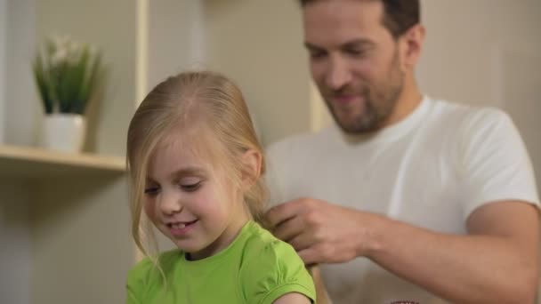 Feliz padre soltero trenzando el cabello de la hija, cuidando a la querida niña — Vídeos de Stock