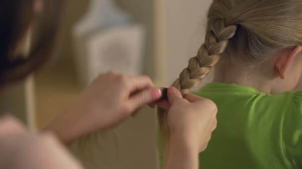 Hermana mayor o niñera trenzando el cabello de la niña, mujer cuidando del niño — Vídeo de stock