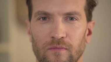 Kendine güvenen zeki genç adam kameraya bakarak farklı renkli gözlü