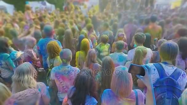 Счастливая толпа молодых людей бросает голубой порошок в воздух, наслаждаясь фестивалем красок — стоковое видео