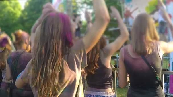 Молодые женщины тусуются на фестивале под открытым небом, наслаждаются диджеем, машут руками — стоковое видео