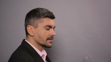 Maden suyu bardaktan içiyor ve başparmak gösterilmesini elbiseli memnun erkek
