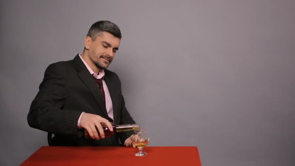 Homem atraente em terno preto sentado no café e degustação de conhaque caro, alegria — Vídeo de Stock