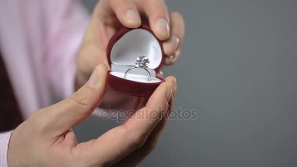 Мужчина вручает обручальное кольцо возлюбленной, женщина держит подарок и целует мужчину — стоковое видео