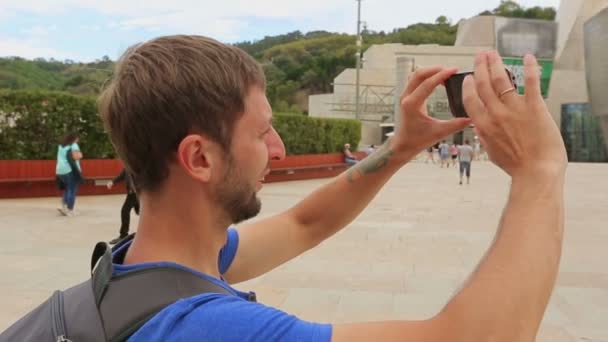 Człowiek, dostosowując ustawienia swojego aparatu telefonu komórkowego i robienia zdjęć, w pobliżu Muzeum — Wideo stockowe