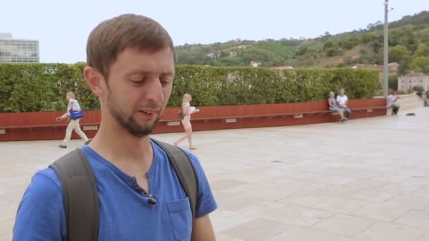 Divertido turista haciendo caras para la cámara, tomando selfie cerca de hito famoso — Vídeo de stock