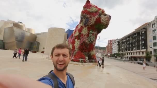 Manliga turist tar selfie nära stor blomma skulptur i Bilbao, Spanien — Stockvideo