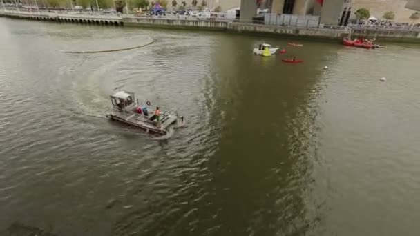 Муниципальные службы моторных лодок очистка городской реки, сбор мусора из воды — стоковое видео