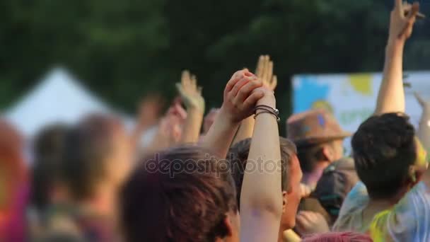 Joyous crowd covered in colorful powder stretching and waving hands at Holi fest — Stock Video