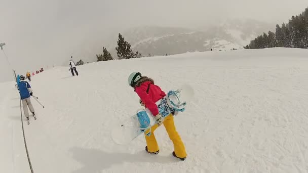 Спортивная молодая женщина с тяжелым сноубордом на вершину горы, зимние каникулы — стоковое видео