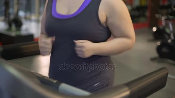Mujer joven gorda corriendo en la cinta de correr, trabajando duro para perder el exceso de peso — Vídeo de stock