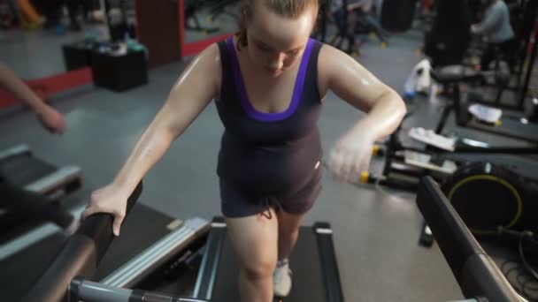 Exhausted overweight woman walking on treadmill, suffering health problems — Stock Video