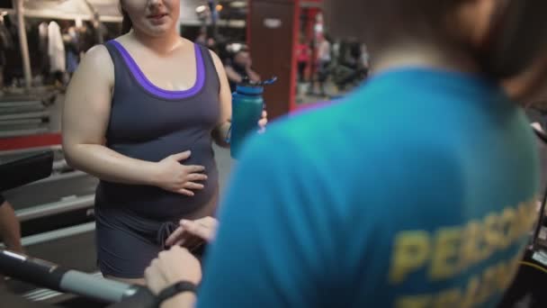 Zwangere vrouw raadpleging met personal trainer op zwangerschap oefeningen in de sportschool — Stockvideo