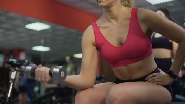Kvinna med perfekt kropp gör hantel övningar i gymmet, aktiv livsstil — Stockvideo