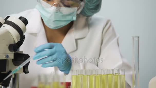 Biólogo trabajando en laboratorio, científico viendo la muestra de bacterias en el microscopio — Vídeo de stock