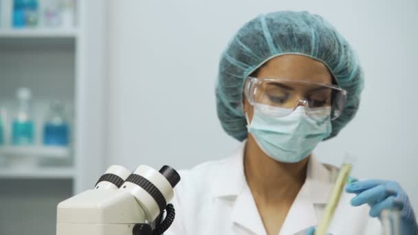 Ассистент биологической лаборатории проверяет жидкости в медицинских трубах на прозрачность — стоковое видео