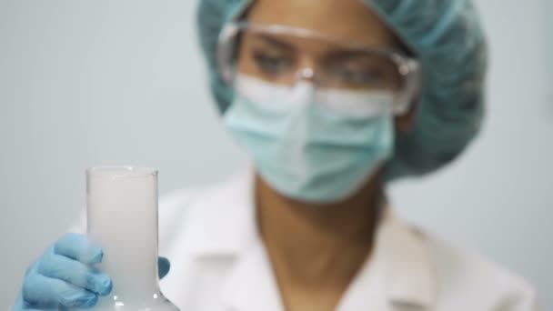 Young female scientist holding flask with evaporating acid in hand, laboratory — Stock Video