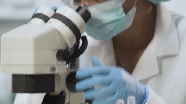 Técnico de laboratorio que usa microscopio para análisis microbiológicos, medicina — Vídeos de Stock