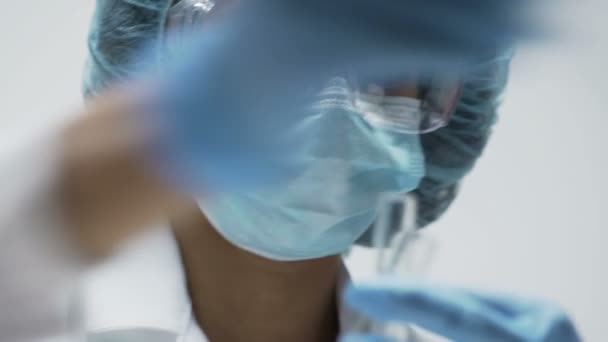 Cientista adiciona gotas de substância azul em tubos de ensaio e olha para a reação — Vídeo de Stock