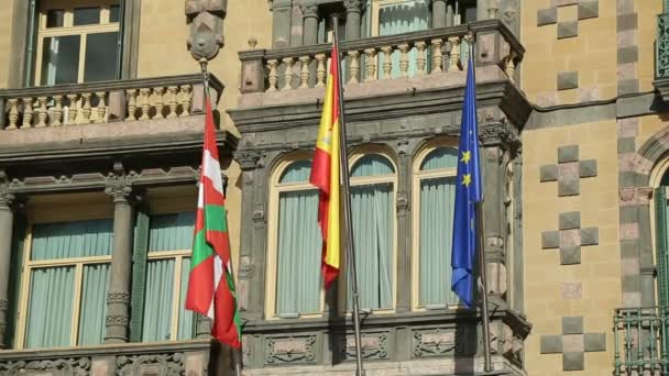 Флаги стран ЕС, Испании и Басков размахивают на фасаде здания правительства — стоковое видео