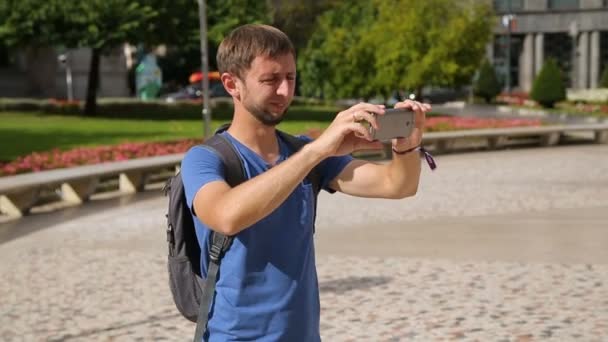 ガジェットは、夏休みに都市景観のパノラマ写真を撮る男性旅行者 — ストック動画