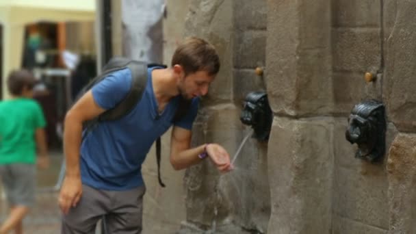 Turista masculino refrescante con agua de Dog Fountain en Bilbao, paseo peatonal — Vídeos de Stock