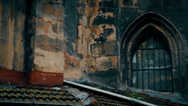 Old wall of abandoned gothic building with shabby roof and barred dirty window — Stock Video