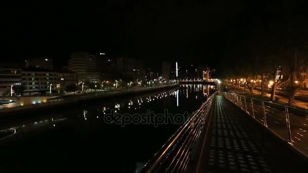 People walking Zubizuri bridge, illuminated night cityscape of Bilbao, panorama — Stock Video