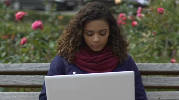 Ziemlich gemischte Renndame öffnet Laptop und plaudert mit Freund im Park — Stockvideo
