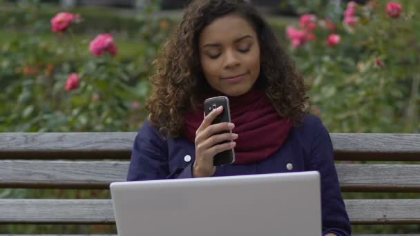 Biracial female journalist sitting at park and calling employer, freelancer — Stock Video