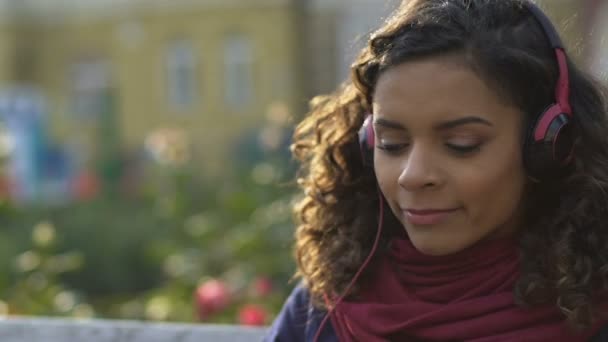 Detail šťastná žena ve sluchátkách poslouchat oblíbenou píseň venku, hudba — Stock video