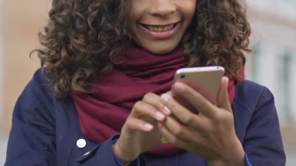 Молода багаторасова жінка переглядає зображення на смартфоні, спілкується з другом — стокове відео