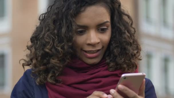 Молодая двуличная женщина смотрит смешное видео на смартфоне, современные технологии — стоковое видео