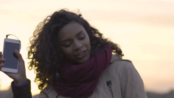 Młoda kobieta biracial muzyce i tańcach o zachodzie słońca, świętować życie — Wideo stockowe