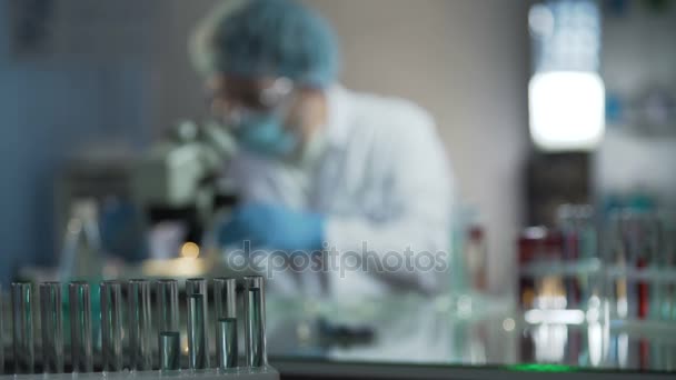 Científico ajustando microscopio antes de examinar las muestras de sangre del paciente en el laboratorio — Vídeo de stock