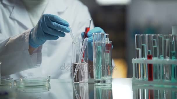 Медицинский аналитик проводит биохимические исследования образцов крови в своей лаборатории — стоковое видео