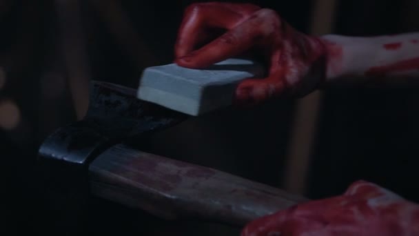Manos de psicópata cubiertas de sangre, afilando hacha, preparándose para un cruel asesinato — Vídeo de stock