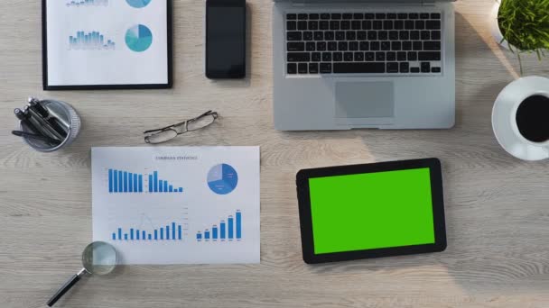 Visão superior do local de trabalho do escritório, tablet com tela verde deitada na mesa, aplicativo — Vídeo de Stock