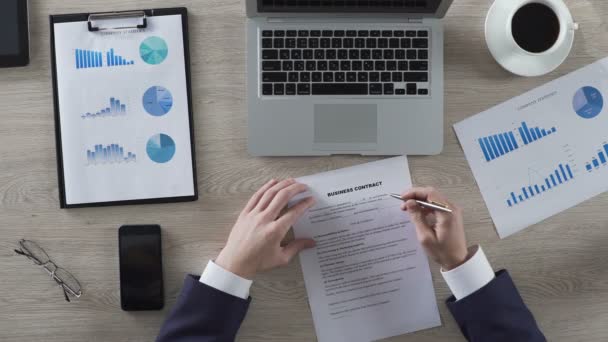 Chefe de departamento lendo contrato de negócios atentamente, visão superior do local de trabalho — Vídeo de Stock