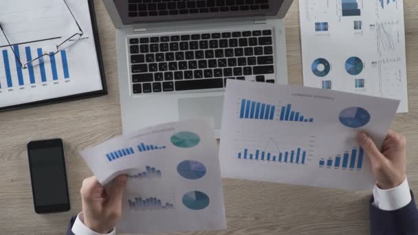 Empresário comparando dois gráficos e inserindo dados no computador portátil — Vídeo de Stock