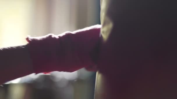 Кулаки сильного человека разбивают боксерскую грушу в тренажерном зале, борясь за достижение цели — стоковое видео