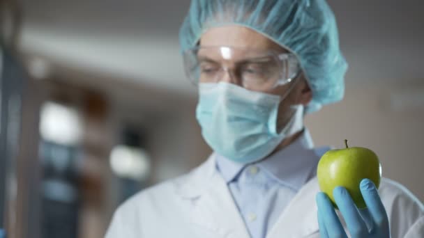 Laboratorní pracovník nástřikem jablka s chemikáliemi, přidání vůně a šťavnatost — Stock video