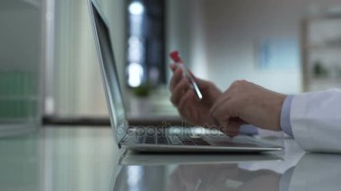 Tıp araştırmacısı alarak test tüpü tablodan bilgi üstünde laptop yazılacak