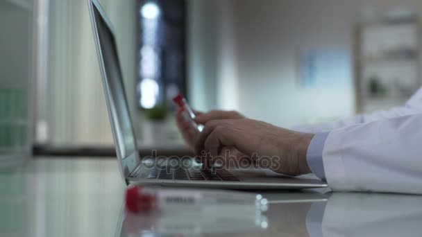 Trabajador de laboratorio escribiendo en el ordenador, muestra de virus en tubo de ensayo, prevención de epidemias — Vídeos de Stock