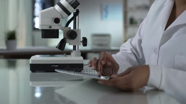 Ricercatore di microbiologia che lavora su tablet in laboratorio, controllando i risultati dei test — Video Stock