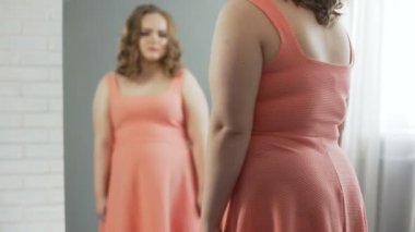 Tombul kız depresyon ayna, her görünüm hakkında üzgün önünde ağlıyor