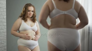 Aynada, onun yağ gövdesi utanç yansıması bakarak iç çamaşırı obez Bayan